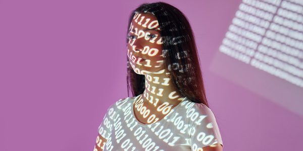 una chica con el rostro cubierto por una proyección de código binario