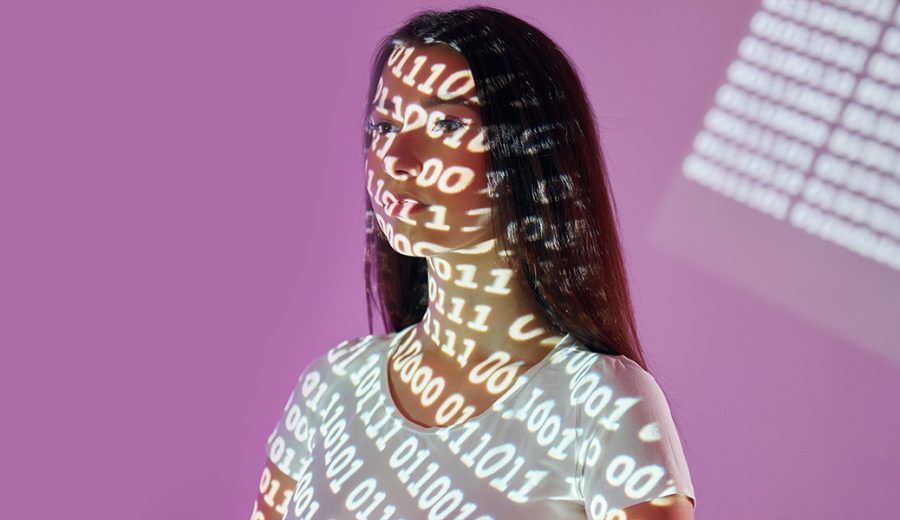 una chica con el rostro cubierto por una proyección de código binario